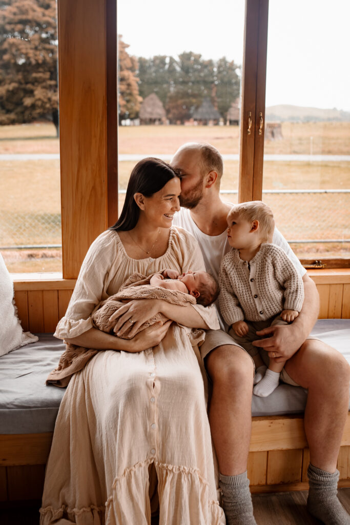 Toddler cuddling newborn baby at home during a lifestyle session by Hawkes Bay newborn photographer