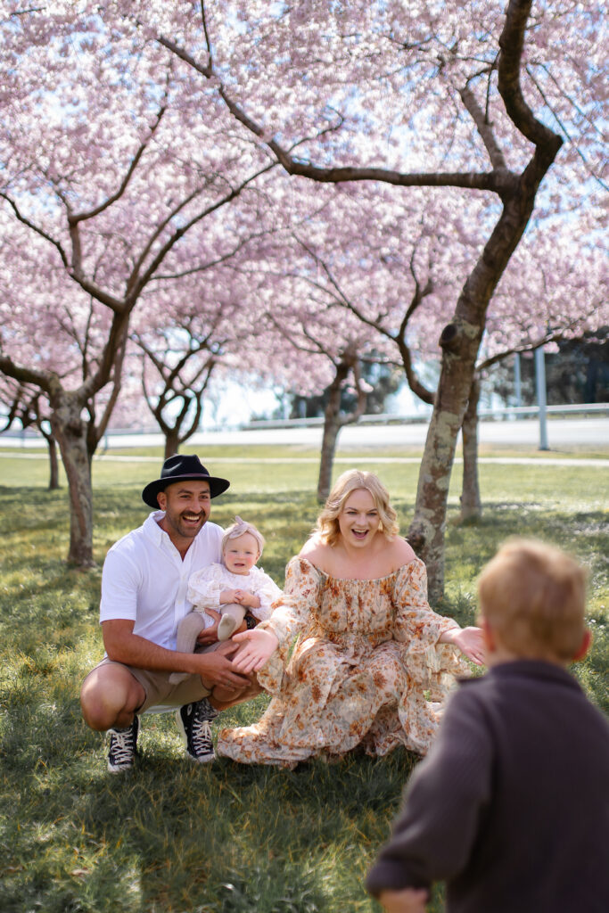 Mum cuddling her young son under blooming cherry blossoms at Pākōwhai Regional Park in Hawke's Bay.