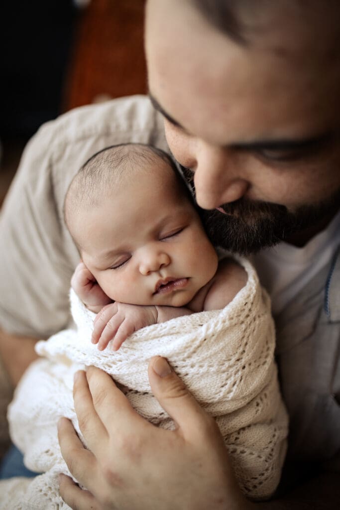 Newborn Baby sleeping in dads arms during an newborn baby in home photoshoot in Hawkes Bay NZ